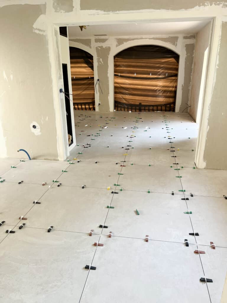 Pose Carrelage : Avancement Travaux Rénovation Intérieure Maison Intérieur en rénovation : carrelage clair posé au sol avec système de nivellement. Murs et arches en cours de finition, chantier actif.